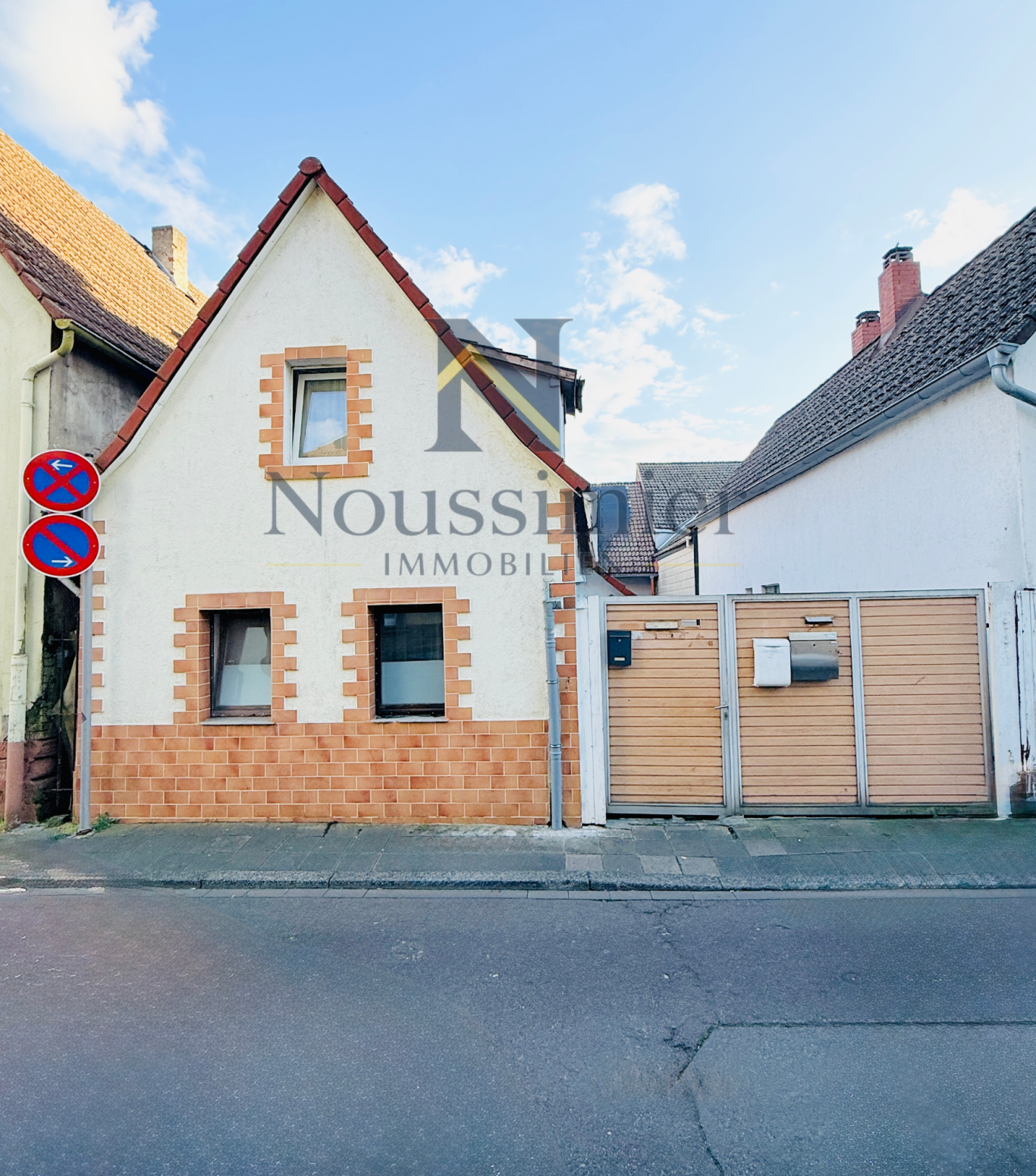 EFH in Ludwigshafen mit Einnahmenpotenzial Fachwerkhaus mit beschrifteter Fassade und angrenzendem Parkplatz in einer Stadt.